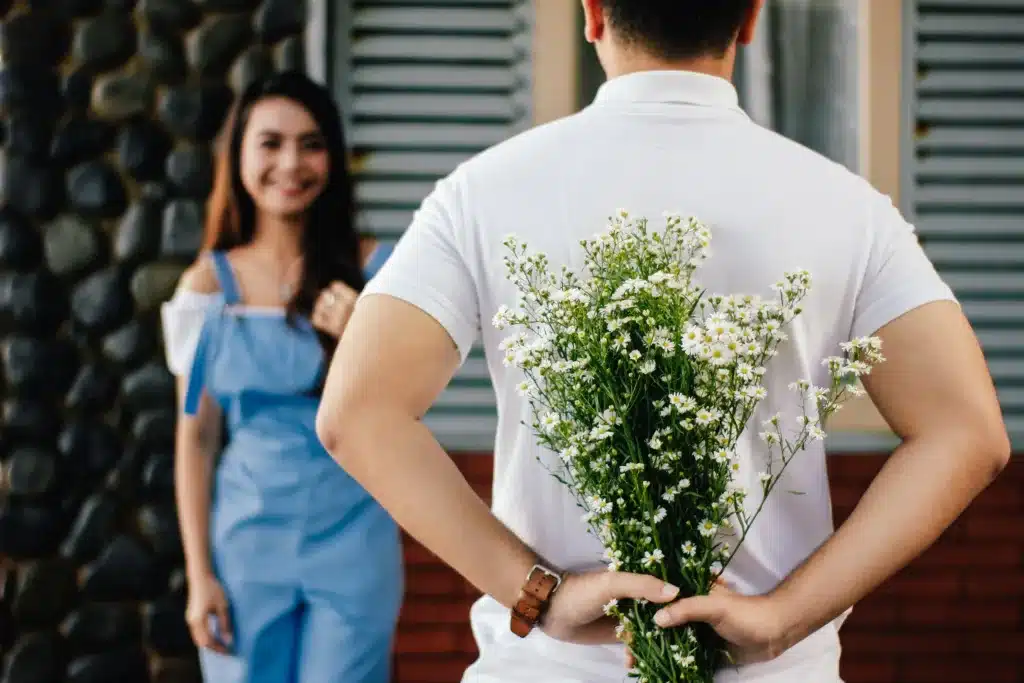 ADHD and Toxic Relationships; what you need to know. A man holding flowers behind his back for a woman in the background. 