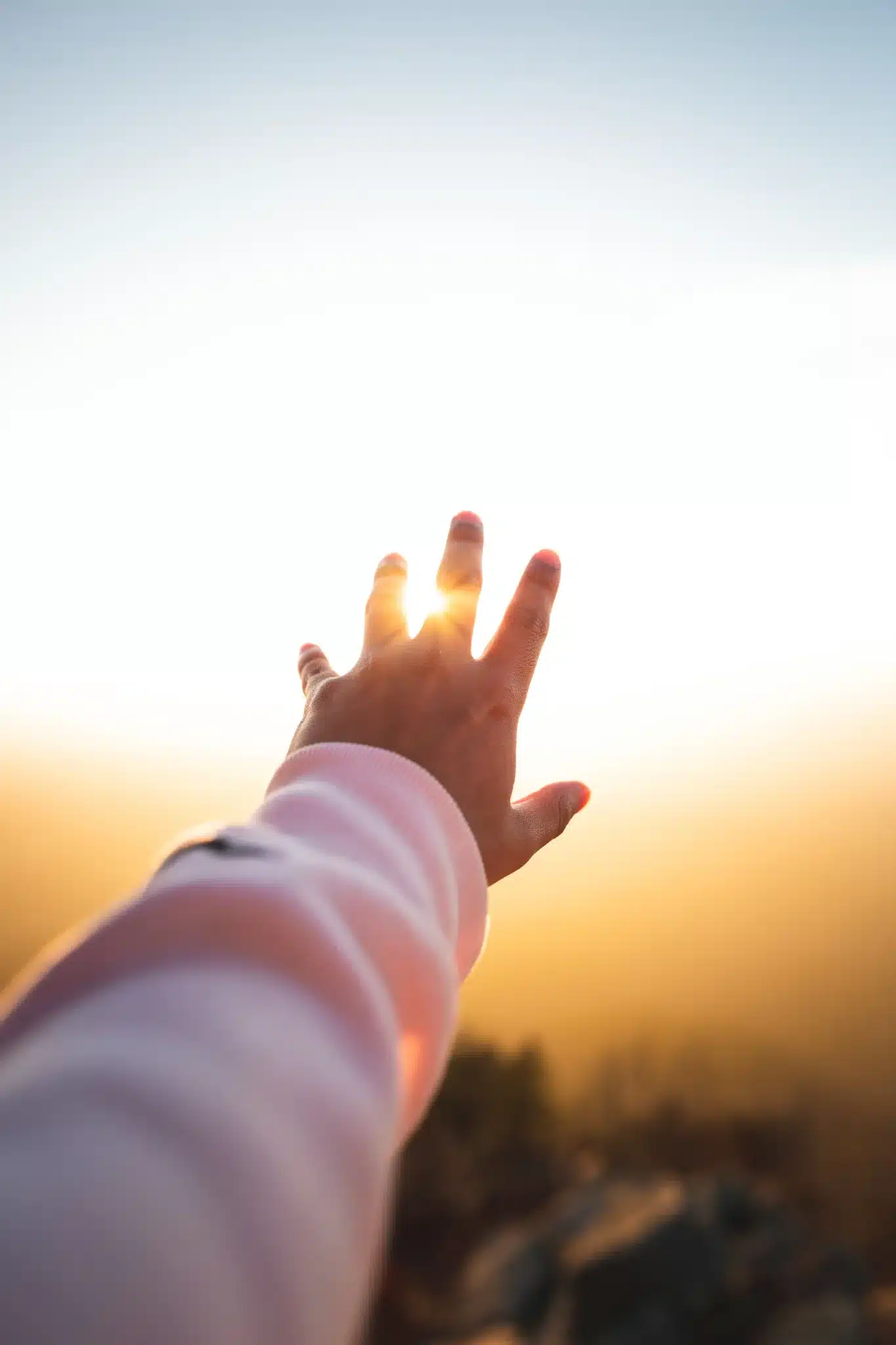 Hand reaching towards the sunset with the lighting behind it. 5 Out of the box approaches to managing ADHD symptoms