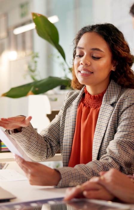 A female insurance agent sitting with a female client at the desk. They're reviewing insurance paperwork together.
