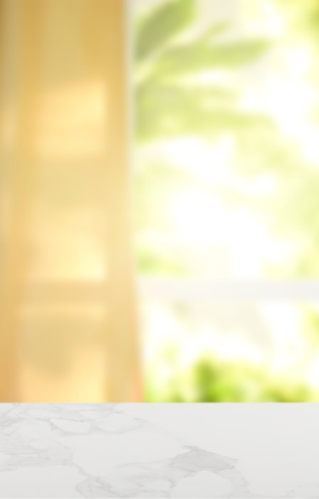 A close-up view shows a white countertop illuminated by sunshine that is coming in through a window.