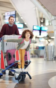 Parents and their young daughter are excited about the flight, with multiple suitcases on a holiday trip.