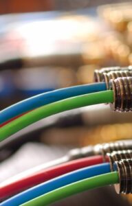 A close-up of red, blue, and green cables plugged into audio ports on equipment, with metallic connectors in focus.