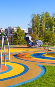 A sprawling outdoor playground with updated features and different play sections. There are benches for parents.