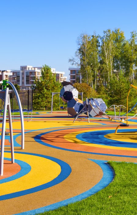 A sprawling outdoor playground with updated features and different play sections. There are benches for parents.